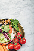 Blick von oben auf eine gesunde Mahlzeit mit Tomaten und Grünzeug auf einem Teller