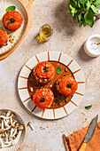 Top view of stuffed tomatoes with brown rice and nuts on a ceramic plate