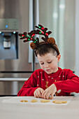 Boy in festive Christmas jumper decorating biscuits