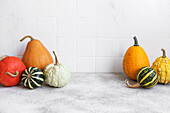 Pumpkin decor on the table over white tile background.