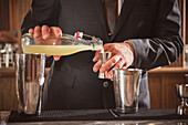 Bartender pouring alcohol from a bottle into a cocktail measuring cup