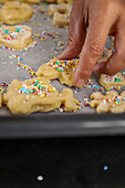 Adding sprinkles to animal-shaped sugar cookies