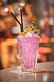 Pink cocktail with ice cubes in glass on counter