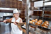 Handwerklicher Bäcker holt Gebäck aus dem Ofen