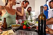 Verschiedene Freunde genießen Getränke und bereiten Essen in der Küche zu