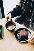 Stylish Caucasian woman with pigtails enjoying coffee and dessert