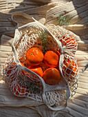 Cosy atmosphere with mandarins in a mesh bag on a knitted blanket