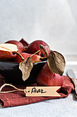 Fresh organic pears with dried leaves and label on a rustic background