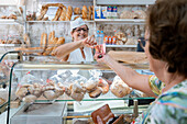 Baker serving a woman in a bakery shop
