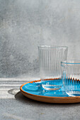 Empty Ribbed Glasses on a Blue Ceramic Plate with Light