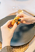 Abgeschnittene Hände essen eine Krokette auf einem eleganten Teller
