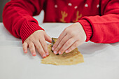A child uses a cookie cutter during Christmas baking