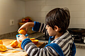 Young boy squeezing fresh orange juice in the kitchen