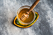 Top view of organic honey in a jar with a ladle