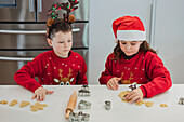 Zwillinge backen Weihnachtsplätzchen in festlichen Outfits