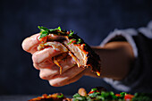 Frau mit leckerem Rippchen-Taco in der Hand, Nahaufnahme, dunkler Hintergrund