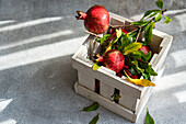 Fresh pomegranates in a wooden crate on a sunny day