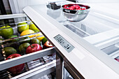 Offener Kühlschrank mit frischen Früchten und Temperaturanzeige