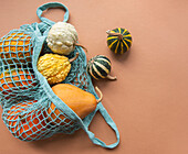 Autumn composition with assorted pumpkins in eco string bag