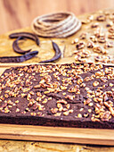 Chocolate cake with walnut topping on a rustic wooden board