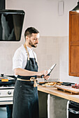 Private chef in the kitchen, examining the knife with a concentrated look