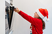 Young girl adjusting the oven at Christmas time