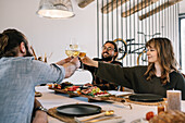 Friends toast with white wine at a cosy dinner party