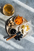 View from above of a Brie cheese platter with olives, wine and vegetables