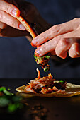 A woman's hand assembles a delicious rib taco with fresh toppings