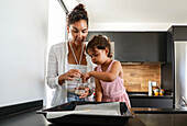 Mother and daughter baking biscuits in the kitchen
