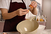 Close-up of hands cracking an egg for baking in a kitchen