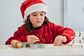 Young girl baking biscuits in festive Christmas outfit