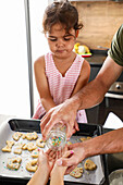 Young girl helping to decorate biscuits with family