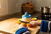 A child preparing fresh orange juice in a cosy kitchen