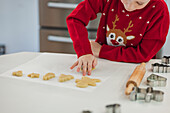 Child in festive jumper baking Christmas biscuits