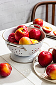 Frische rote Pflaumen mit Wassertropfen in einem weißen Sieb