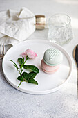Elegant arrangement of macarons and a rose on a white plate