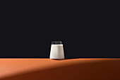 Glass of milk on an orange-coloured surface, minimalist arrangement