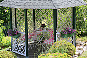 Sommerpavillon mit Blumenkästen und karierter Tischdecke im Garten