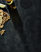 Grilled flatbread, lemon wedge and beer on a dark background