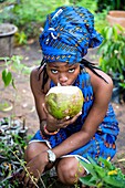 Benin, Cotonou, woman drinking a cocnut