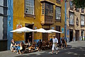 Spain, Canary Islands, Tenerife Island, La Laguna, man in traditional Canarian costume in front of a cafe terrace and a colonial house with yellow facade and wooden balcony