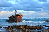 Südafrika, Westkap, versunkenes Wrack bei Sonnenuntergang an der felsigen Küste von Kap Aghulas, wo der Indische Ozean auf den Atlantik trifft