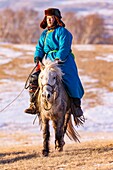 China, Innere Mongolei, Provinz Hebei, Zhangjiakou, Bashang-Grasland, ein mongolischer Reiter auf einem Pferd, der auf einer schneebedeckten Wiese läuft