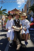 Spain, Canary Islands, Tenerife Island, children in traditional Canarian costume sitting on a decorated float during a romería, a traditional celebration