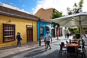 Spain, Canary Islands, Palma Island, Los Llanos de Aridane, strollers in an alley lined with colorful colonial houses and restaurant terraces