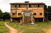 Benin, Ouidah, woman standing in font of an old colonial building