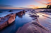 Frankreich, Var, Saint-Raphaël, Sonnenuntergangslichter auf den Felsen des Strandes von Péguière mit dem Massif des Maures im Hintergrund