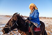 China, Innere Mongolei, Provinz Hebei, Zhangjiakou, Bashang-Grasland, ein mongolischer Reiter auf einem Pferd in einer schneebedeckten Wiese