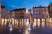 Frankreich, Aveyron, Villefranche de Rouergue, Platz von Notre Dame in der Abenddämmerung und sein leuchtender Brunnen